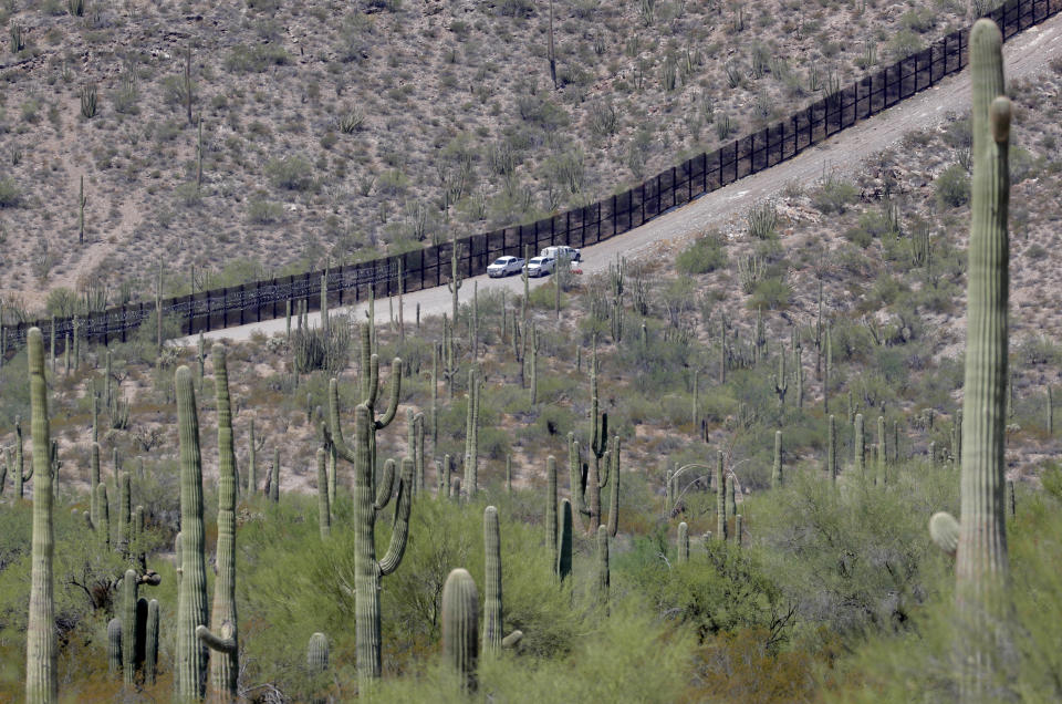 FILE - In this Aug. 22, 2019, file photo, U.S. Customs and Patrol agents sit along a section of the international border wall that runs through Organ Pipe National Monument in Lukeville, Ariz. After a record hot and dry summer, more deaths among border-crossers have been documented in Arizona's desert and mountains. (AP Photo/Matt York, File)