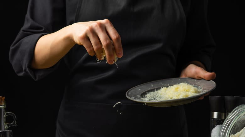 hand sprinkling parmesan cheese