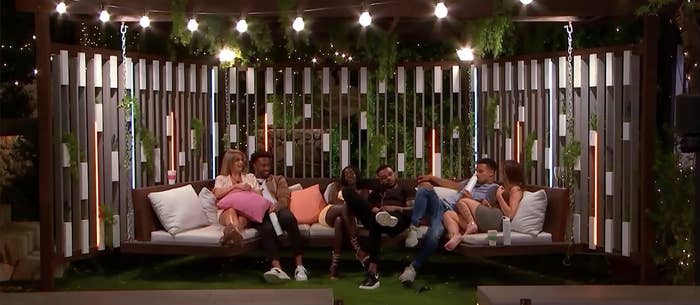 a group of contestants cuddle on the outdoor swing