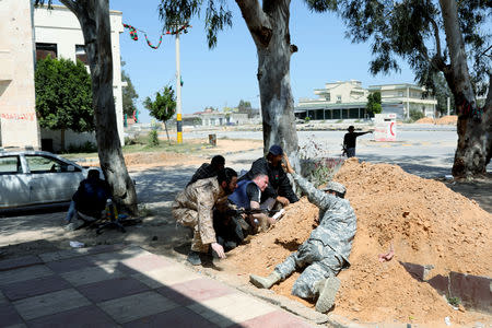 Members of Libyan internationally recognised government forces look for cover during the fighting with Eastern forces at Al-Swani area in Tripoli, Libya April 18, 2019. REUTERS/Ahmed Jadallah