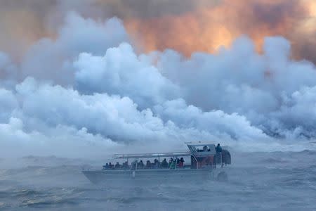 People watch from a tour boat as lava flows into the Pacific Ocean in the Kapoho area, east of Pahoa, during ongoing eruptions of the Kilauea Volcano in Hawaii, U.S., June 4, 2018. REUTERS/Terray Sylvester/Files