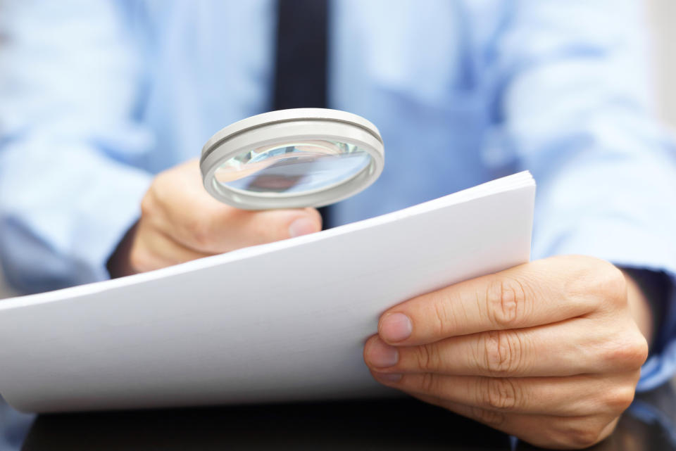 Businessman looking through contract with a magnifying glass