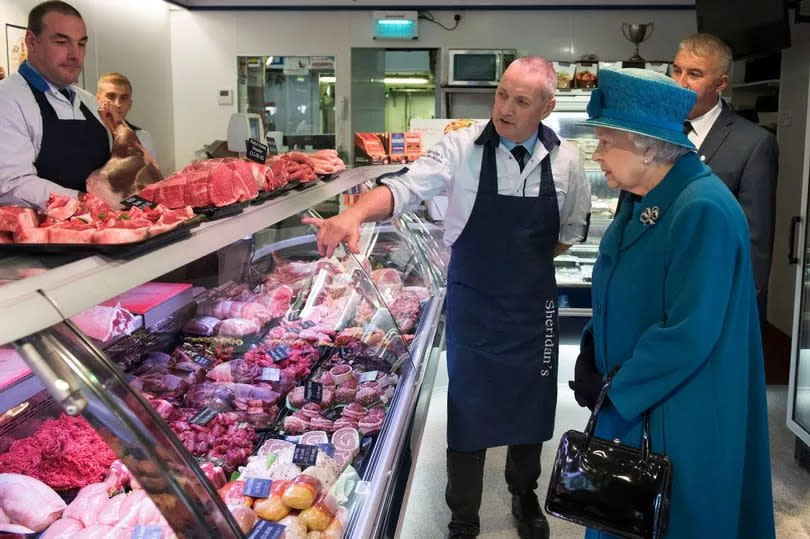 Queen Elizabeth II speaks with co-owners of HM Sheridan Butchers Mr Barry Florence and Mr John Sinclair  during a visit to Ballater in Aberdeenshire