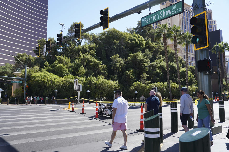 Pedestrians cross the street as police tape blocks a road near the scene where multiple people were stabbed in front of a Strip casino in Las Vegas, Thursday, Oct. 6, 2022. Police say an attacker has killed two people and wounded six others in stabbings along the Las Vegas Strip. (Brian Ramos/Las Vegas Sun via AP)