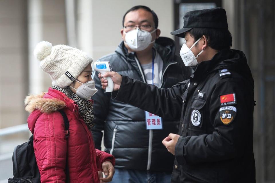 Officials in Wuhan take the temperature of boat passengers before letting them on board | Getty