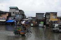 A man on his bike wades through a flooded street in Manila on June 30, 2013. Fresh flooding paralysed parts of the capital on Monday after heavy rain overnight from Tropical Storm Trami