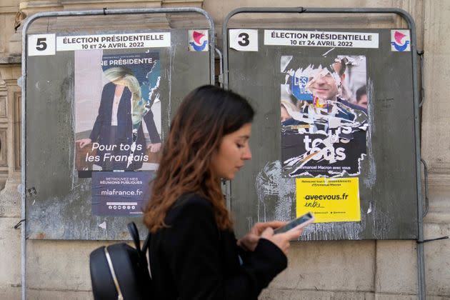 A woman walks in front of torn campaign posters of French President Emmanuel Macron and candidate for the reelection, right, and of far-right presidential candidate Marine Le Pen, left, in Paris, France, Tuesday, April 19, 2022. French President Emmanuel Macron is facing off against far-right challenger Marine Le Pen in France's April 24 presidential runoff. (AP Photo/Francois Mori) (Photo: via Associated Press)