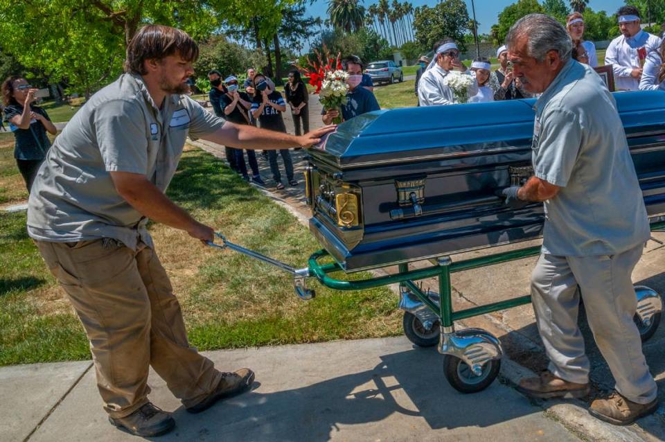 Cemetery workers carry the elegant casket for Dung Tan Nguyen who was a local member of the Vietnamese community and a musician on Wednesday, May 6, 2020, during the coronavirus outbreak. “It would have been the family but there weren’t enough men to carry it,” said his daughter-in-law Trang Nguyen as she explained the COVID-19 restrictions on social distancing at Sacramento Memorial Lawn prevented many from attending the funeral.