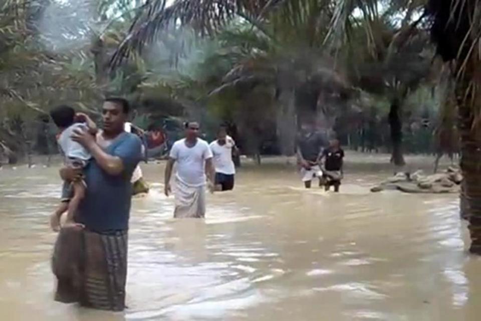 People wade through flood water as they evacuate a flooded area (AFP/Getty Images)