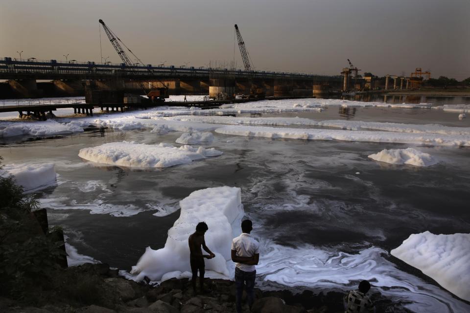 FILE- In this April 22, 2014 file photo, an Indian man dresses after bathing amidst industrial effluence in the river Yamuna in New Delhi, India. As India faces certain water scarcity and ecological decline, the country’s main political parties campaigning for elections have all but ignored environmental issues seen as crucial to India’s vast rural majority, policy analysts say. (AP Photo/Manish Swarup, File)