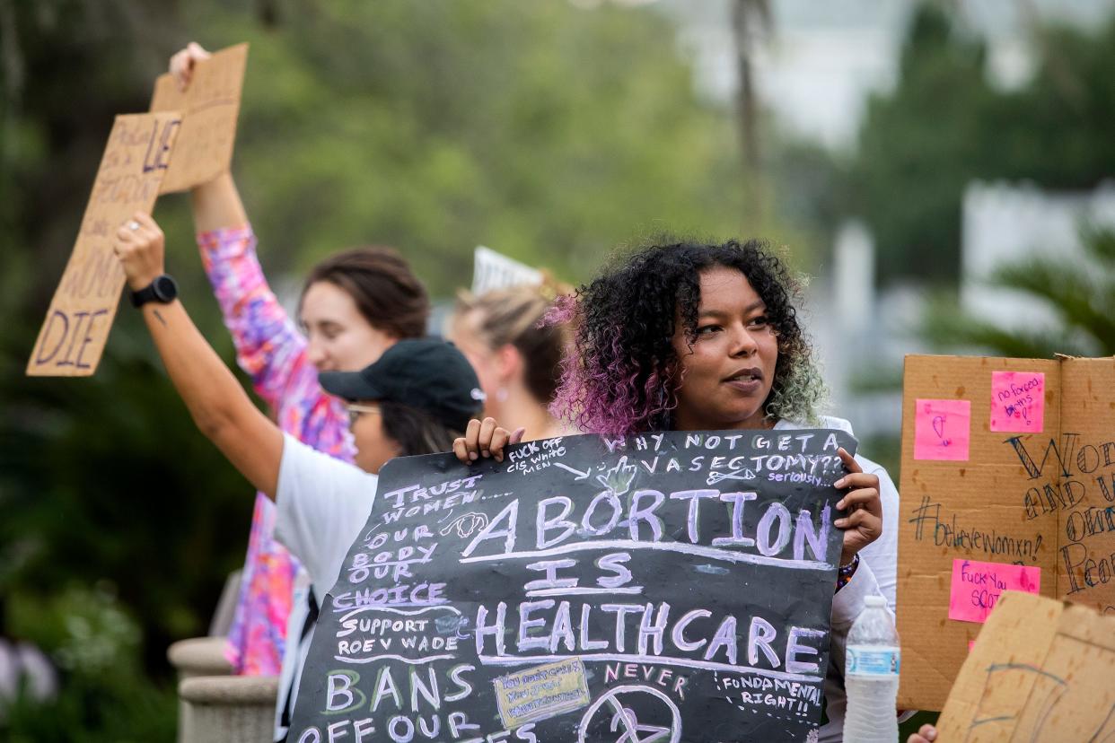 Protesters wave signs for passing cars on Monroe Street in front of the Florida Historic Capitol in Tallahassee, Fla. during a rally protesting the reversal of Roe v Wade on Friday, June 24, 2022. 