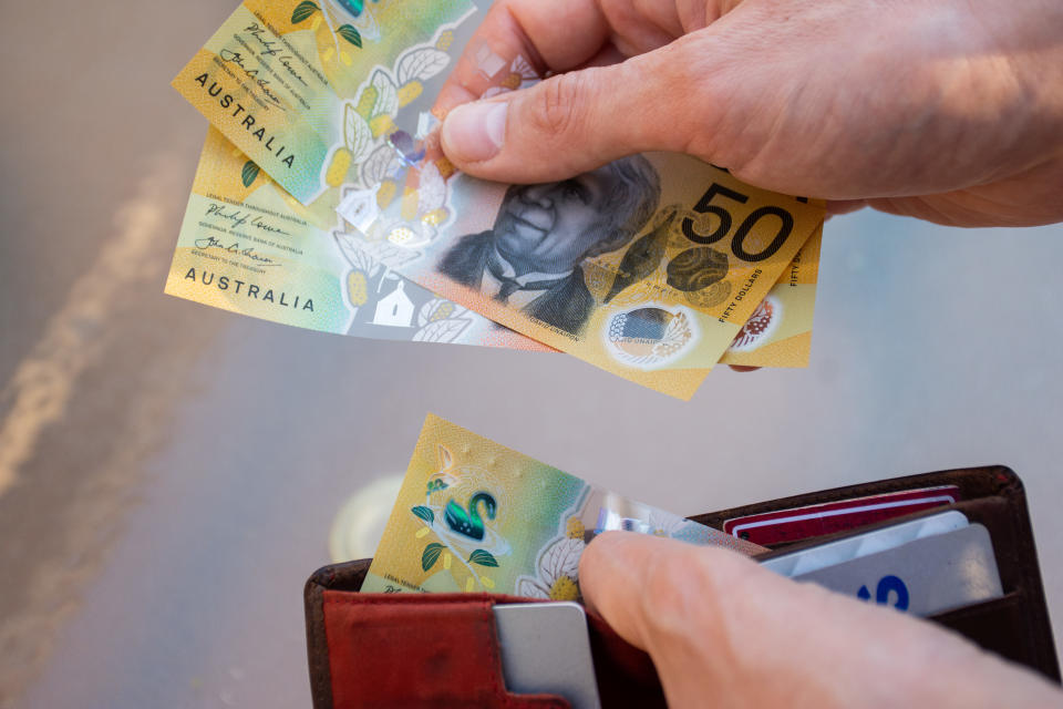 Hands holding a wallet with Australian money.