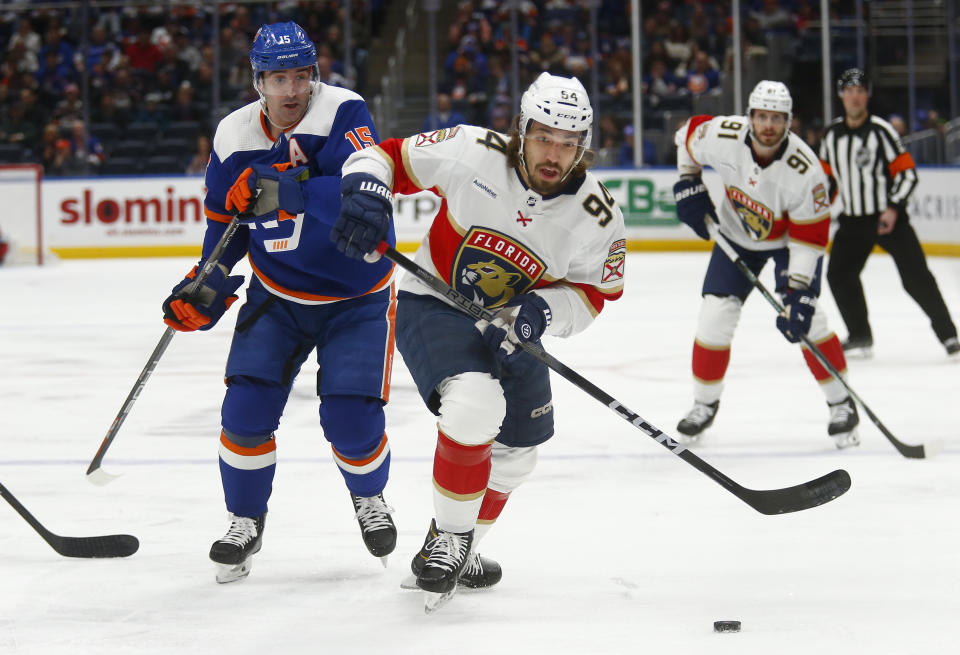 New York Islanders forward Cal Clutterbuck (15) and Florida Panthers forward Ryan Lomberg (94) battle for the puck during the first period of an NHL hockey game, Saturday, Jan. 27, 2024, in Elmont, N.Y. (AP Photo/John Munson)