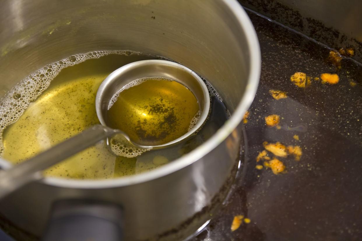 Pot and spoon on a dirty sink in a domestic kitchen.