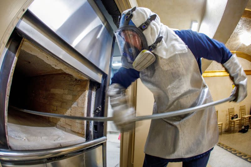 FILE PHOTO: Funeral coordinator and crematory technician Eddie Martinez collects remains from a cremation furnace at the Hollywood Forever cemetery