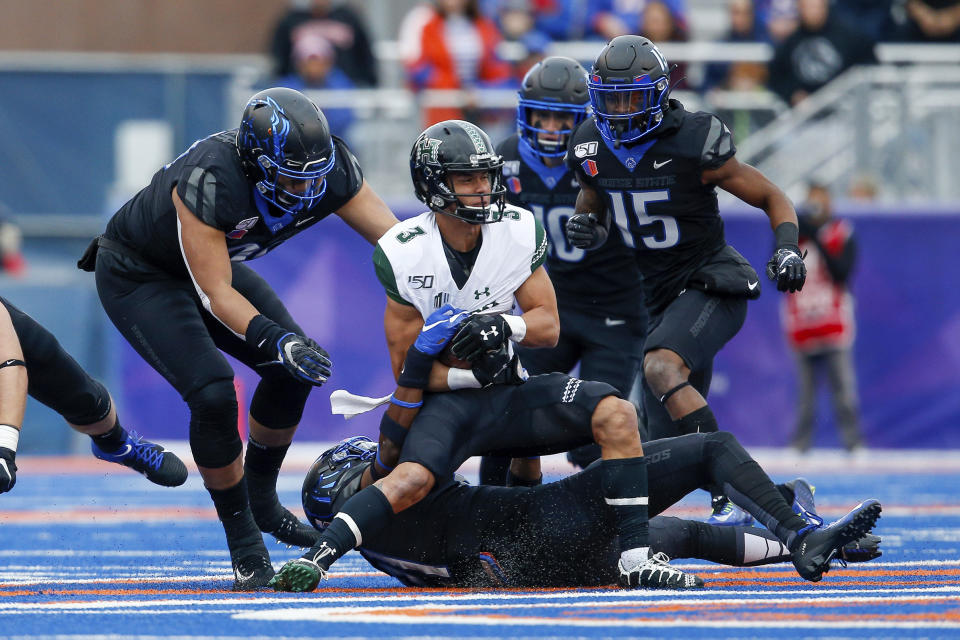 Hawaii wide receiver Jason-Matthew Sharsh, center, is pulled down by Boise State defensive back Tyreque Jones, bottom, as Boise State linebacker Curtis Weaver, left, and Boise State cornerback Jalen Walker, right, move in to help with the tackle during the first half of an NCAA college football game for the Mountain West Championship Saturday, Dec. 7, 2019, in Boise, Idaho. (AP Photo/Steve Conner)