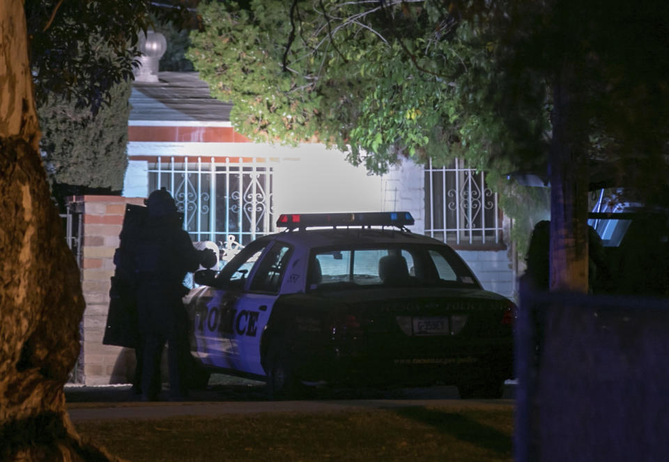 In this Thursday, Nov. 29, 2018 photo, a Tucson Police Department Officer stands stands outside the house where a suspect is holed up following a shooting in Tucson, Ariz. A deputy U.S. marshal serving a felony arrest warrant was shot and killed outside the Tucson house. The suspect was arrested after an hour-long standoff at the home. (Ron Medvescek/Arizona Daily Star via AP)