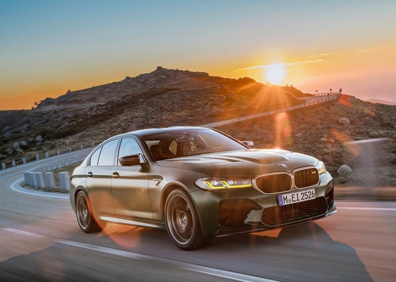 A BMW M5 CS driving on a gorgeous mountain road in front of a sunset