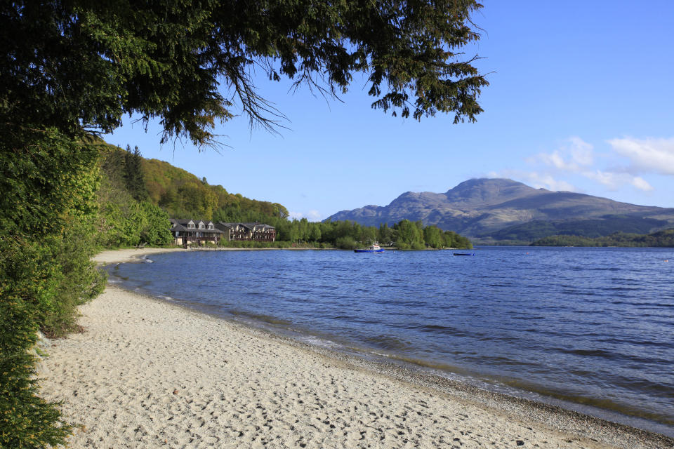 The sandy beach at luss which is located on the west side of loch lomond.  The loch Lomond hotel and lodges is visible beyond. [Photo: Visit Scotland]                                                                                                                                                                                                                                                                   