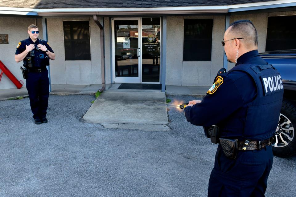Wan Boros, field training officer with the DeFuniak Springs Police Department, demonstrates the BolaWrap restraint system on police officer in training Josh McKee. The BolaWrap shoots a small cord that is designed to wrap around legs or arms and restrain a subject without causing injury.