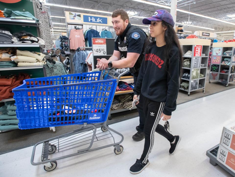 Pensacola Police Department officer Ken McMahon, left, pushes the cart for Kayllah Allen, 18, during the Shop with a Cop shopping spree at the Academy Sports + Outdoors in Pensacola on Thursday, Dec. 21, 2023.