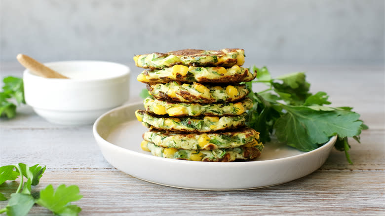 Corn fritters stacked on a white plate