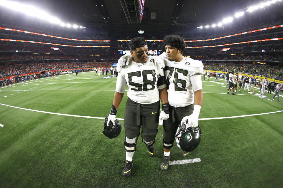 Oregon offensive linemen Penei Sewell (58) and Jonah Tauanu'u (76) walk off the field after the team's 27-21 loss to Auburn following an NCAA college football game, Saturday, Aug. 31, 2019, in Arlington, Texas. (AP Photo/Ron Jenkins)