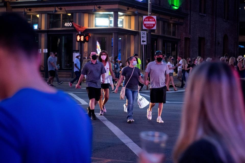People wear masks while crossing the street on Lower Broadway in Nashville, Tenn., Friday, Aug. 7, 2020.