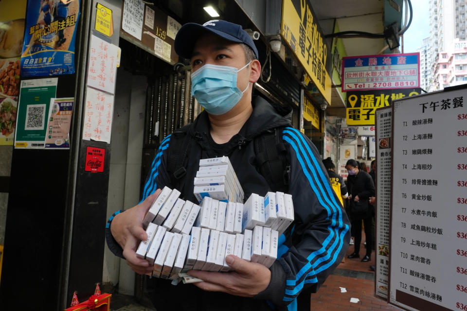 A man wearing face mask carries COVID-19 antigen test kits after purchasing at a market in Hong Kong, Monday, Feb. 28, 2022. (AP Photo/Vincent Yu)