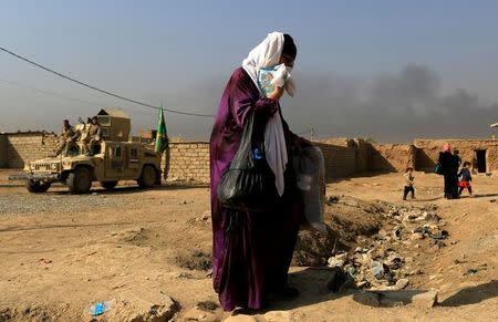 A woman who is fleeing the fighting between Islamic State and the Iraqi army in the Intisar district of eastern Mosul, walks past a military humvee while heading to safer territory in Iraq November 7, 2016. REUTERS/Zohra Bensemra/Files