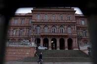 Photographed through a fence, a worker cleans the entrance of the government house, hours before Argentine President Alberto Fernandez swears-in his new Economy Minister Silvina Batakis in Buenos Aires, Argentina, Monday, July 4, 2022. Batakis replaces Martin Guzman who quit unexpectedly Saturday, posting his seven-page resignation letter on Twitter. (AP Photo/Natacha Pisarenko)