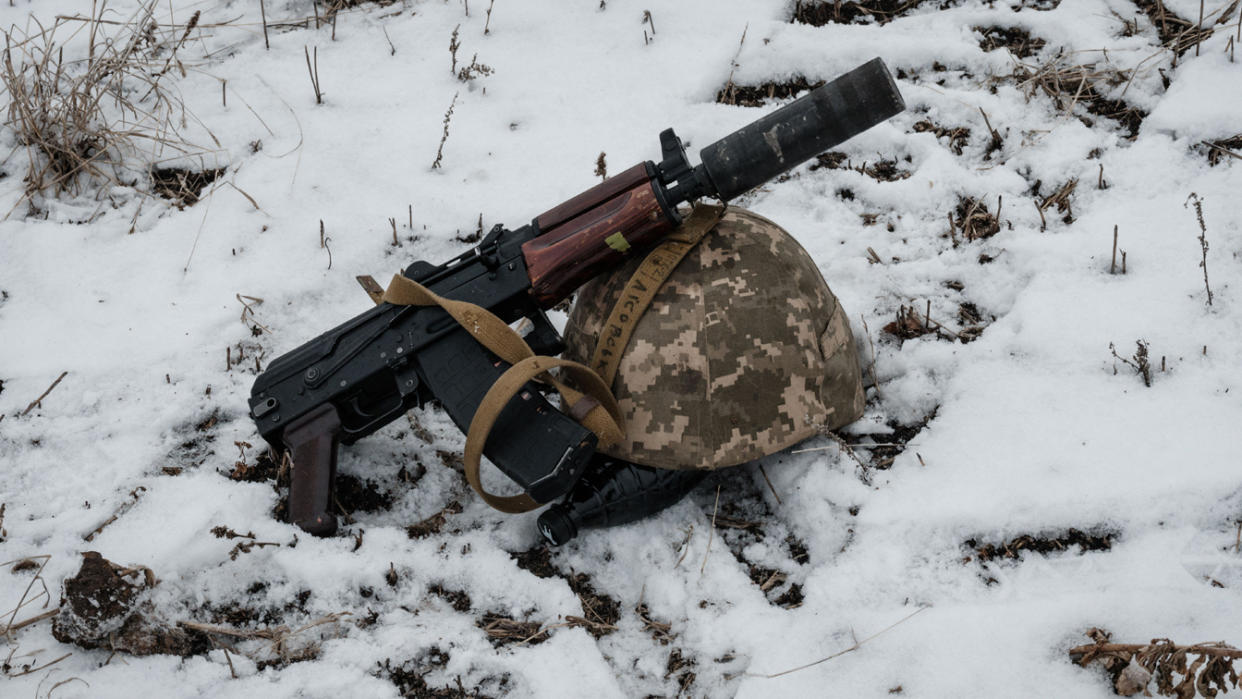 A weapon and a helmet on the snow-covered ground.