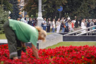 Belarusian opposition supporters hold flowers and flash victory signs during a protest in Minsk, Belarus, Thursday, Aug. 20, 2020. Demonstrators are taking to the streets of the Belarusian capital and other cities, keeping up their push for the resignation of the nation's authoritarian leader. President Alexander Lukashenko has extended his 26-year rule in a vote the opposition saw as rigged. (AP Photo/Dmitri Lovetsky)