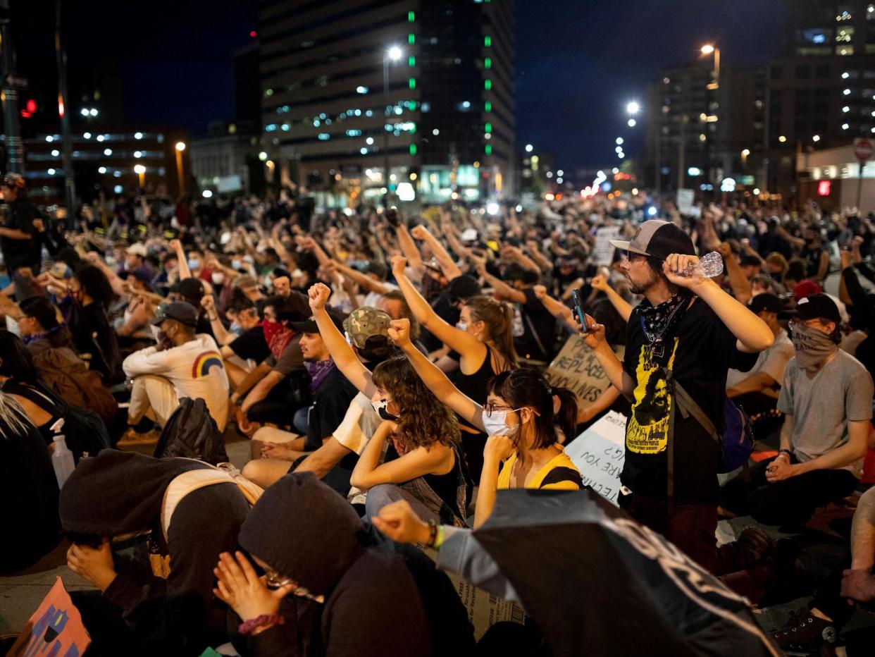 Demonstrators in Denver raise their fists as they sit in silence for nine minutes in a peaceful protest against the death in Minneapolis police custody of George Floyd: (Reuters)