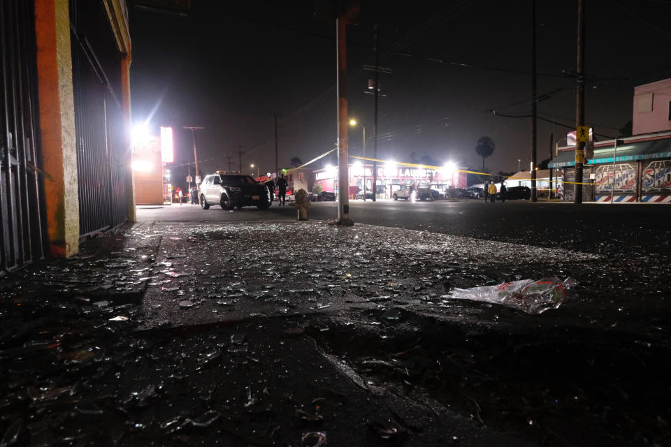 Broken glass sits on a sidewalk and street after a fireworks explosion in Los Angeles on Wednesday, June 30, 2021. A cache of illegal fireworks seized at a South Los Angeles home exploded, damaging nearby homes and cars and causing injuries, authorities said. (AP Photo/Ringo H.W. Chiu)