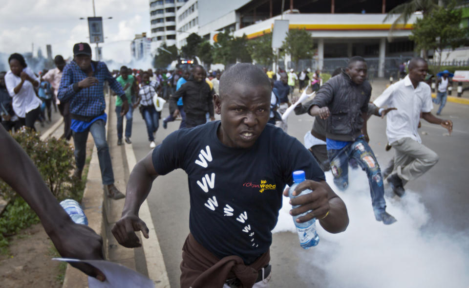 Opposition supporters flee from tear gas grenades fired by riot police during a protest in downtown Nairobi, Kenya Monday, May 16, 2016. Kenyan police have tear-gassed and beaten opposition supporters during a protest demanding the disbandment of the electoral authority over alleged bias and corruption. (AP Photo/Ben Curtis)