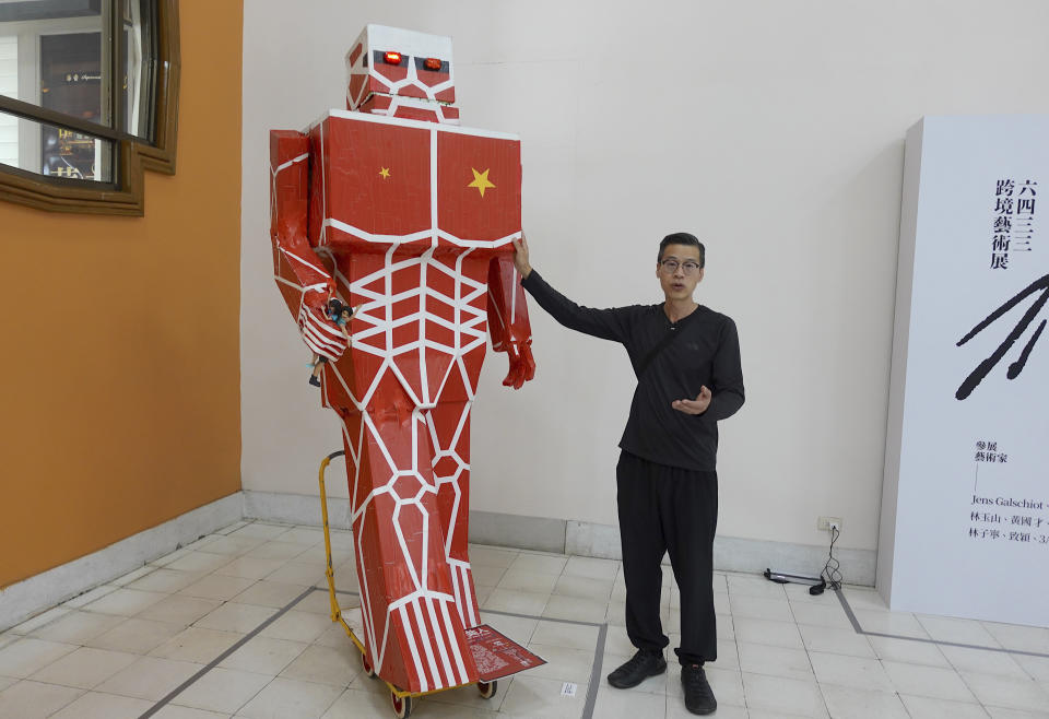 Kacey Wong, a Hong Kong artist who moved to Taiwan in 2021, stand next to his installation art piece depicting a giant red robot at the exhibition in Taipei, Taiwan on June 11, 2022. Taiwan just 400 miles from Hong Kong, is close not just geographically, but also linguistically and culturally. It offered the freedoms that many Hong Kongers were used to and saw disappearing in their hometown. (AP Photo/Johnson Lai)