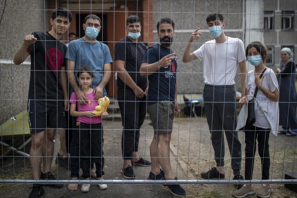 Migrants from Iraq speak to journalists through a fence at the refugee camp in the village of Verebiejai, some 145km (99,1 miles) south from Vilnius, Lithuania, Sunday, July 11, 2021. Migrants at the school in the village of Verebiejai, about 140 kilometers (87 miles) from Vilnius, haven't been allowed to leave the premises and are under close police surveillance. Some have tested positive for COVID-19 and have been isolated in the building. (AP Photo/Mindaugas Kulbis)