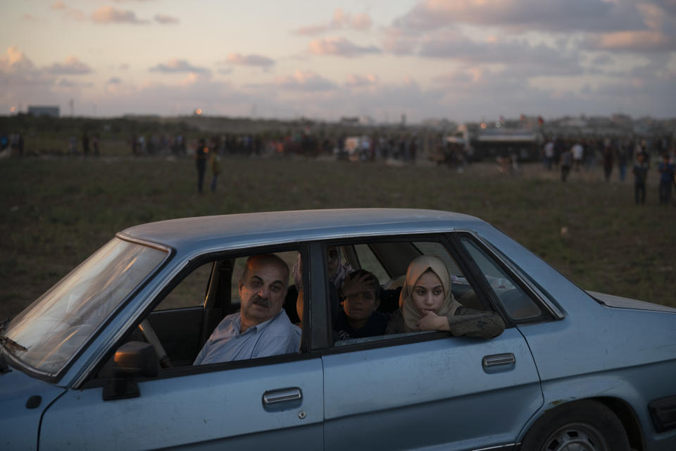 In this Friday, Sept. 14, 2018 photo, Khalil Ayesh sits in his car with his family watching Palestinian protesters at the Gaza Strip's border with Israel, east of Gaza City. "I bring them every week," Ayesh said of the three children in the back seat -- his son and daughter, and his daughter's neighbor, "so they can understand what this struggle is about." (AP Photo/Felipe Dana)