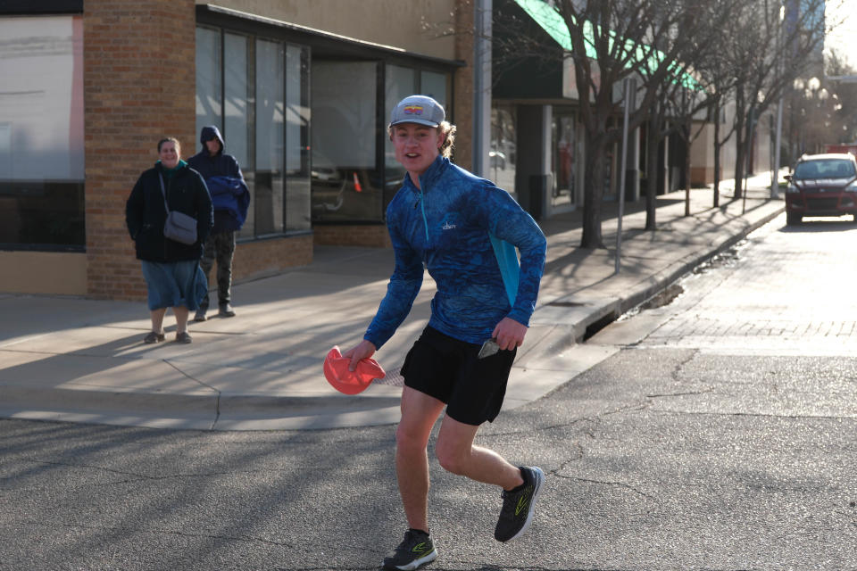 Jackson Knapp, the eventual winner of the Center City Mural Run 10K, stops to pick up the cap of an Amarillo Globe-News photographer Saturday in downtown Amarillo.