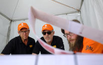 In this photo taken Friday, June 21, 2019, framed by a sheet of tickets, FlipTix CEO Jaime Siegel, center, works with his team to set up their tent at the entrance to the Clusterfest comedy event in San Francisco. The company's application lets people who leave a venue early sell their ticket and lets someone who wants the remainder of the ticket buy it. (AP Photo/Eric Risberg)