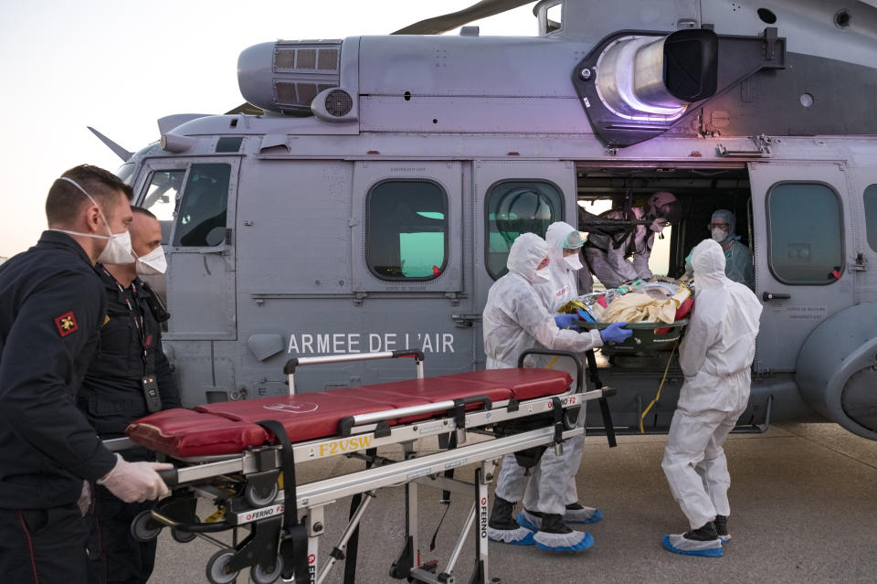 In this photo provided by the French Army Thursday, April 2, 2020, medical staffs evacuate a patient infected with the Covid-19 virus, Wednesday April 1, 2020 at Orly airport, south of Paris. The operation aims at relieving hospitals in the Paris region, hardly hit by the coronavirus. The new coronavirus causes mild or moderate symptoms for most people, but for some, especially older adults and people with existing health problems, it can cause more severe illness or death. (Julien Fechter/DICOD via AP)