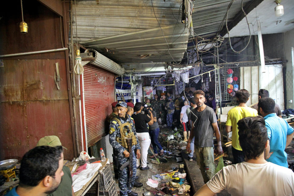 People and security forces gather at the site of a bombing in Wahailat market in Sadr City, Iraq, Monday, July 19, 2021. A roadside bomb attack targeted a Baghdad suburb Monday, killing at least 18 people and wounding dozens of others at a crowded market, Iraqi security officials said. (AP Photo/Khalid Mohammed)