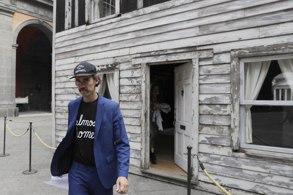 Artist Ryan Mendoza walks in front of the house of U.S. civil rights campaigner Rosa Parks, which he rebuilt for public display, in Naples, Italy, Tuesday, Sept. 15, 2020. The rundown, paint-chipped Detroit house where Parks took refuge after her famous bus boycott is on display in a setting that couldn't be more incongruous: the imposing central courtyard of the 18th century Royal Palace. (AP Photo/Gregorio Borgia)