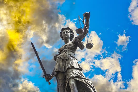 A statue of Lady Justice, set against swirling clouds.