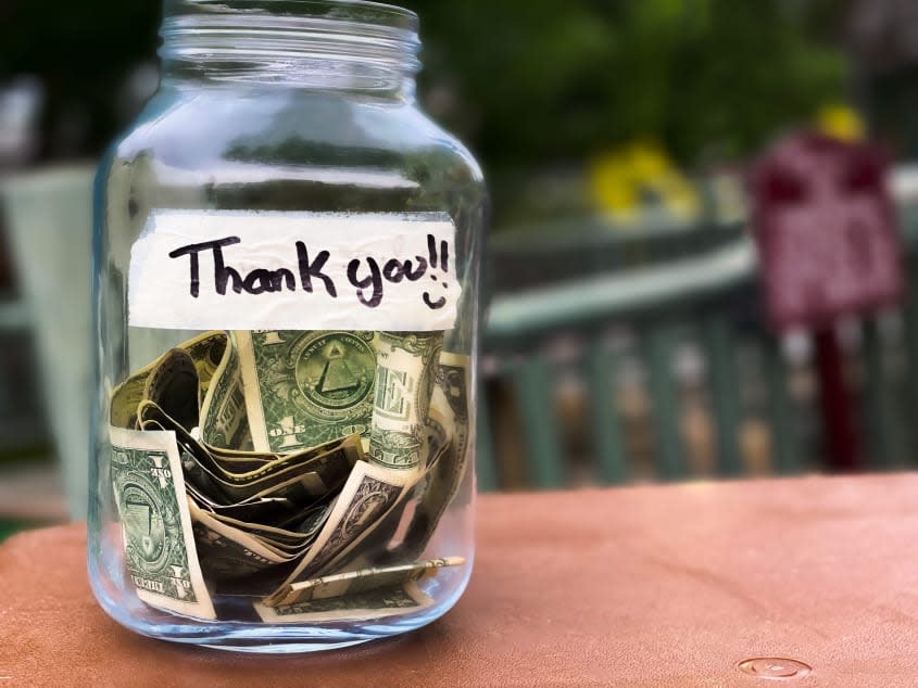 A tip jar containing dollar bills