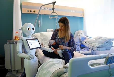 New recruit "Pepper" the robot, a humanoid robot designed to welcome and take care of visitors and patients, holds the hand of a newborn baby next to his mother at AZ Damiaan hospital in Ostend, Belgium June 16, 2016. REUTERS/Francois Lenoir