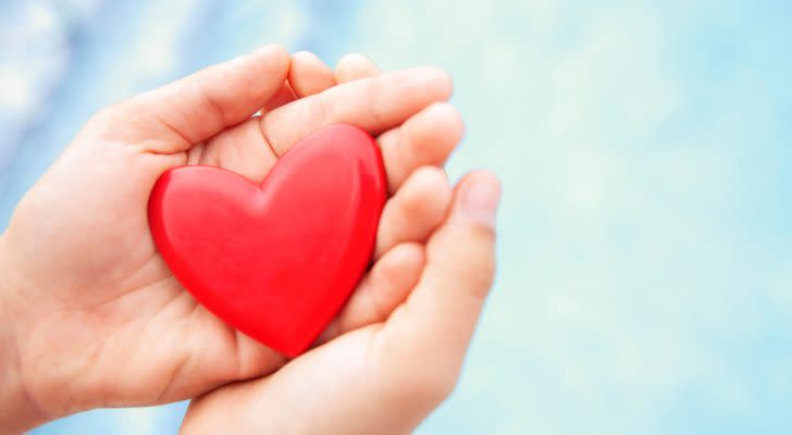 hands holding a red heart shape against blue background symbolizing health