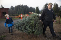 Tim Daley and son Jacob, 9 years, from Tualatin carry their freshly cut Christmas tree at Lee farms on Saturday, Nov. 21, 2020 in Tualatin, Ore. It's early in the season, but both wholesale tree farmers and small cut-your-own lots are reporting strong demand, with many opening well before Thanksgiving. (AP Photo/Paula Bronstein)