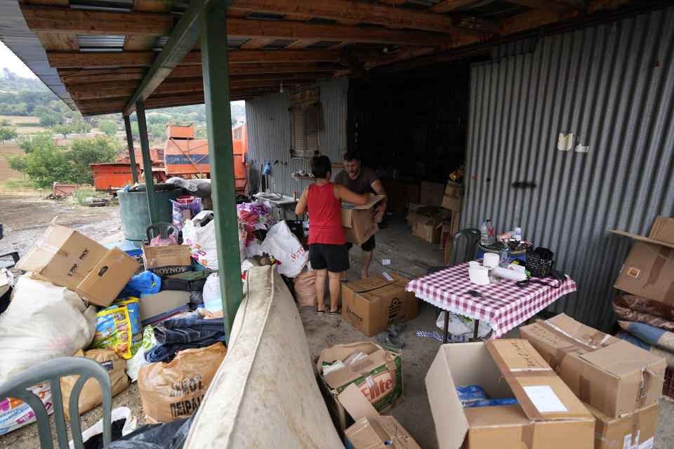 Villagers of Milies stores the boxes of donated goods at Milies village on Evia island, about 181 kilometers (113 miles) north of Athens, Greece, Thursday, Aug. 12, 2021. Greek Prime Minister Kyriakos Mitsotakis says the devastating wildfires that burned across the country for more than a week amount to the greatest ecological catastrophe Greece has seen in decades. (AP Photo/Petros Karadjias)